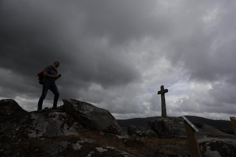 Un hombre camina este miércoles por el lugar de la Cruz do Loureiro, en el concello coruñés de Vimianzo, en una jornada lluviosa en Galicia tras la llegada de un frente atlántico