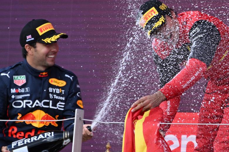 Sergio Pérez, con champagne en mano, junto a Carlos Sainz en el podio