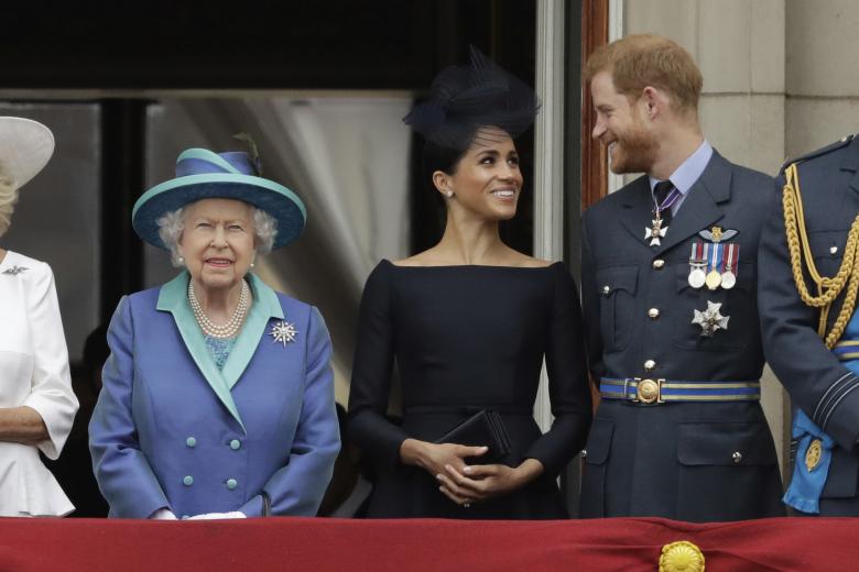 Britain's Queen Elizabeth II, Meghan the Duchess of Sussex and Prince Harry watch a flypast of Royal Air Force aircraft pass over Buckingham Palace in London, Tuesday, July 10, 2018. Various events were held Tuesday to mark the centenary of the RAF. (AP Photo/Matt Dunham)