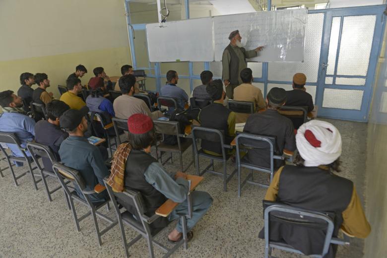In this photo taken on June 7, 2022, members of the Taliban with their classmates attend an economic faculty class at a private university in Kabul. - Since the Taliban swept back to power in August 2021, hundreds of fighters have returned to school -- either on their own, or pushed by their commanders. (Photo by Ahmad SAHEL ARMAN / AFP) / TO GO WITH 'Afghanistan-Taliban-OneYear-education' FOCUS