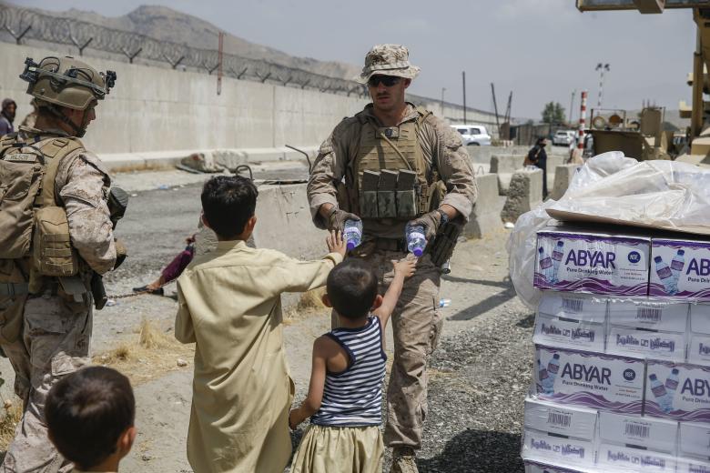 Handout photo dated August 20, 2021 of a U.S. Navy corpsman with Special Purpose Marine Air-Ground Task Force - Crisis Response - Central Command, hands out water to children during an evacuation at Hamid Karzai International Airport, Kabul, Afghanistan.
