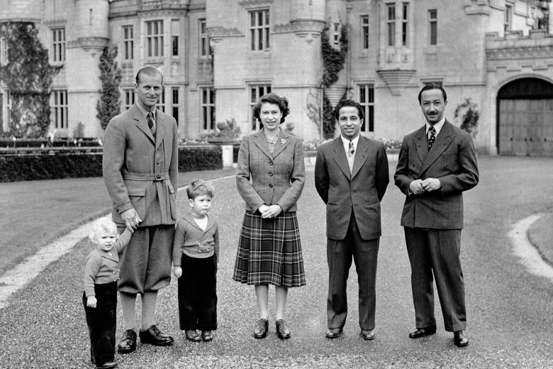 Queen Elizabeth II, wearing a tartan skirt and tweed jacket outside Balmoral Castle with her Royal visitors, King Faisal II and the Regent of Iraq, and the Duke of Edinburgh, Prince Charles and Princess Anne.