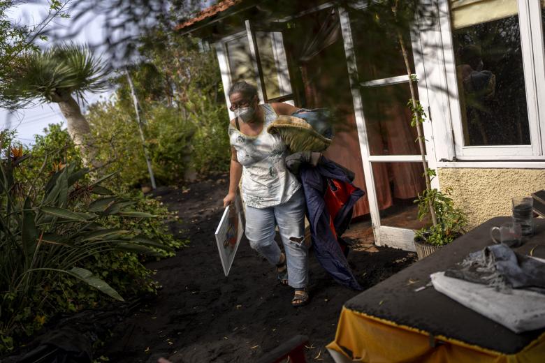 Annette Lowestein, from Germany, collects some of her belongings while leaving her house stalked by the lava that advances towards her neighborhood on the Canary island of La Palma, Spain, Saturday, Oct. 30, 2021.