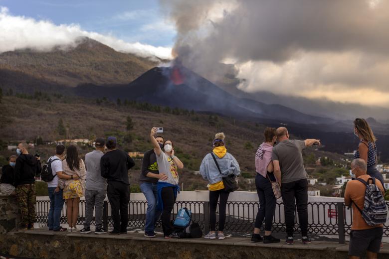 Tourists look and take selfies at a volcano as it continues to erupt on the Canary island of La Palma, Spain, Tuesday, Oct. 26, 2021.