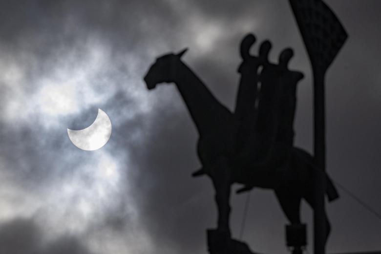 Un eclipse solar parcial se ve detrás de la estatua 'Jinete del Apocalipsis' del artista Bjorn Norgaard en el centro de Malmo, Suecia