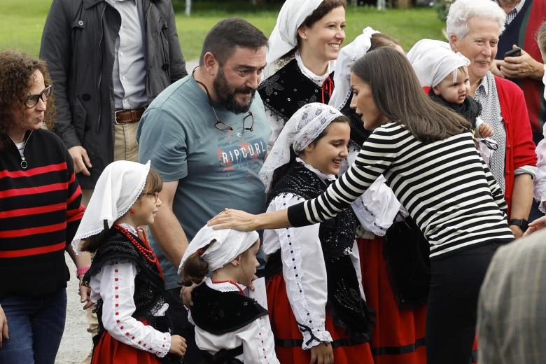 La Reina Letizia saluda a varias niñas vestidas con atuendos regionales en Cadavedo
