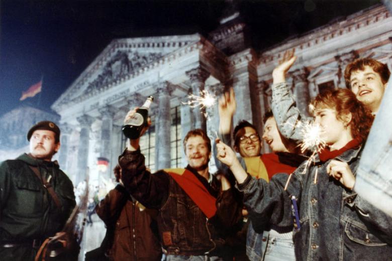 Youth light flares in front of Berlin's Reichstag early Oct. 3, 1990 to celebrate German unification. At left is a riot policeman guarding the parliament building.  (AP Photo/Diether Endlicher)