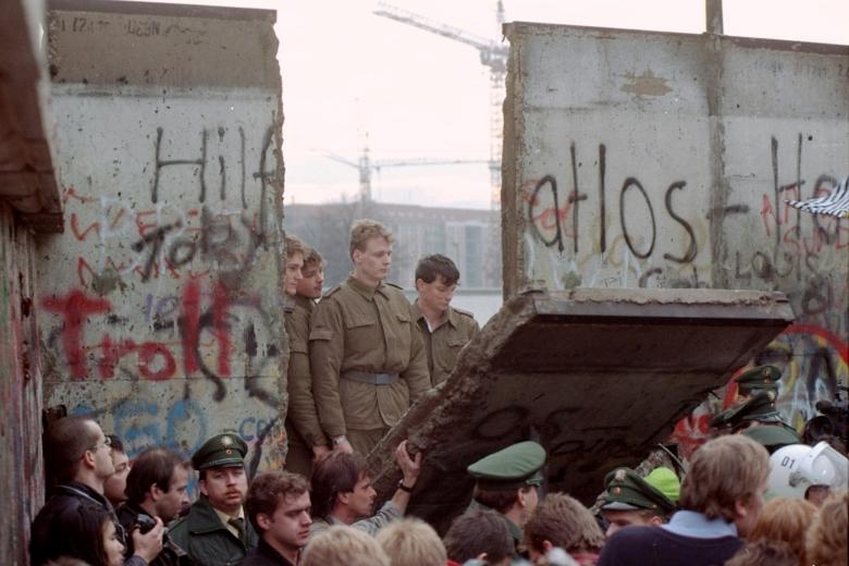 East Berliners get helping hands from West  Berliners as they climb the Berlin Wall which has divided the city since the end of World War II, near the Brandenburger Tor (Brandenburg Gate), early morning, Nov. 10, 1989. The citizens facing the West celebrate the opening of the order that was announced by the East German Communist government hours before.