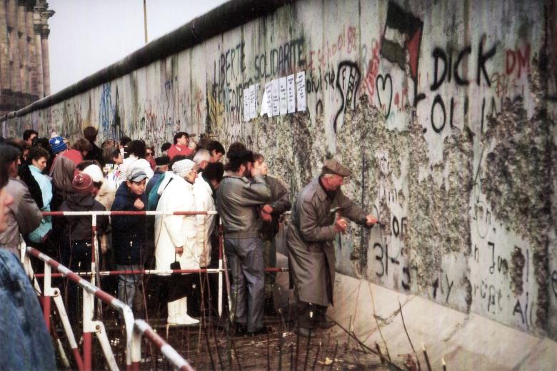 Ciudadanos rompiendo trozos del muro