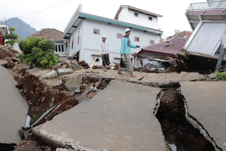 Dos estudiantes de la escuela pasan junto a su internado islámico colapsado causado por un terremoto de magnitud 5.6
