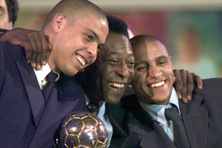 La superestrella del fútbol brasileño Pelé, al centro, con sus compatriotas Ronaldo, a la izquierda, y Roberto Carlos, sonríen mientras posan con el trofeo al jugador del año de la FIFA durante la ceremonia de entrega de premios de la FIFA celebrada en Disneyland París en Marne la Vallee, al este de París, en 1998.