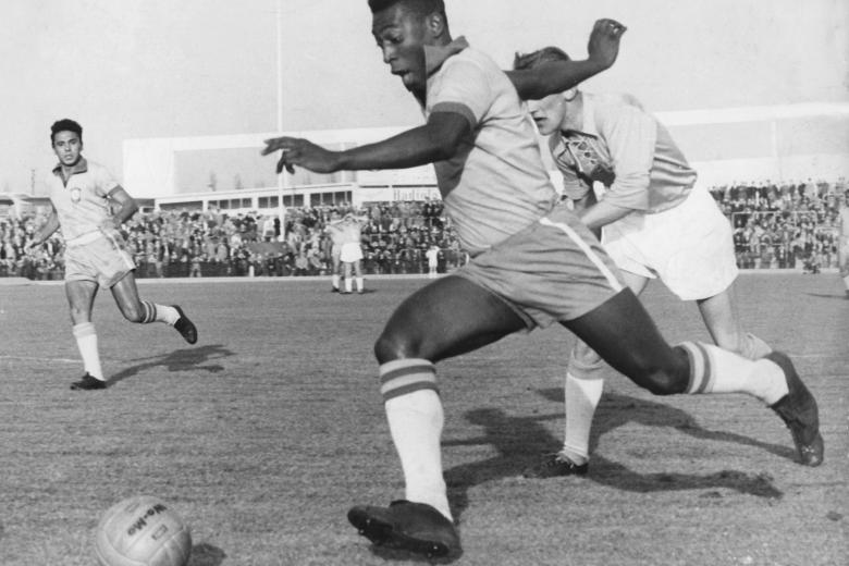 El delantero brasileño Pelé corre con el balón frente a un defensor sueco del club de fútbol Malmoe FF durante un amistoso internacional entre el Malmoe FF y la selección brasileña en Malmoe, Suecia, el 8 de mayo de 1960