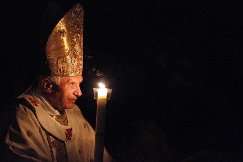 Benedicto XVI portando una vela encendida en la Basílica de San Pedro, durante el comienzo de la Semana Santa