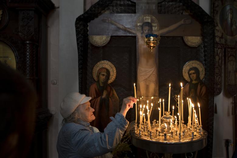 Lithuanian Orthodox believers light a candle during the Palm Sunday Mass inside the Prechistensky, the Cathedral Palace in Vilnius, Lithuania, Sunday, April 9, 2017.