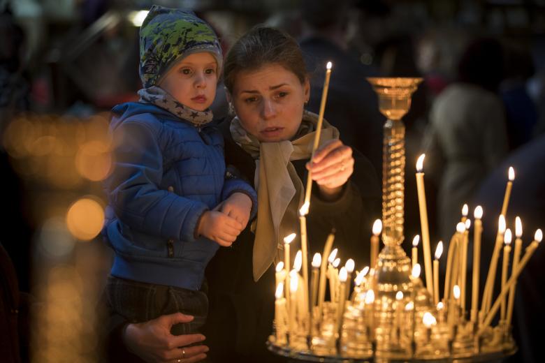 Lithuanian Orthodox believers light a candle during the Palm Sunday Mass inside the Prechistensky, the Cathedral Palace in Vilnius, Lithuania, Sunday, April 9, 2017.