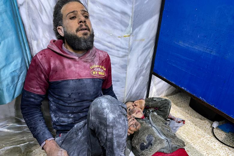 Un padre espera con su hija a ser atendido en un hospital sirio