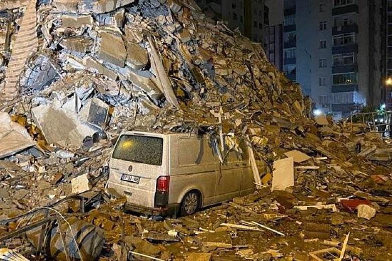 Una furgoneta semienterrada en los escombros de un edificio derrumbado por el terremoto