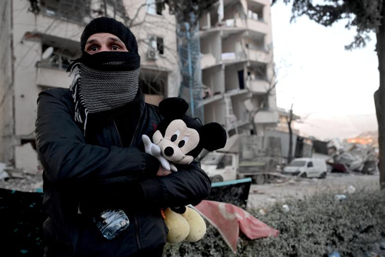 Un hombre sostiene un muñeco de Micky Mouse que pertenece a su sobrino en Kahramanmaras