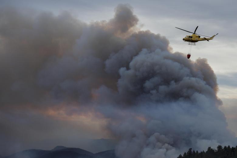 Un helicóptero sobrevuela la columna de humo del incendio forestal declarado el término municipal pasado jueves, en la zona limítrofe de las provincias de Castellón y Teruel