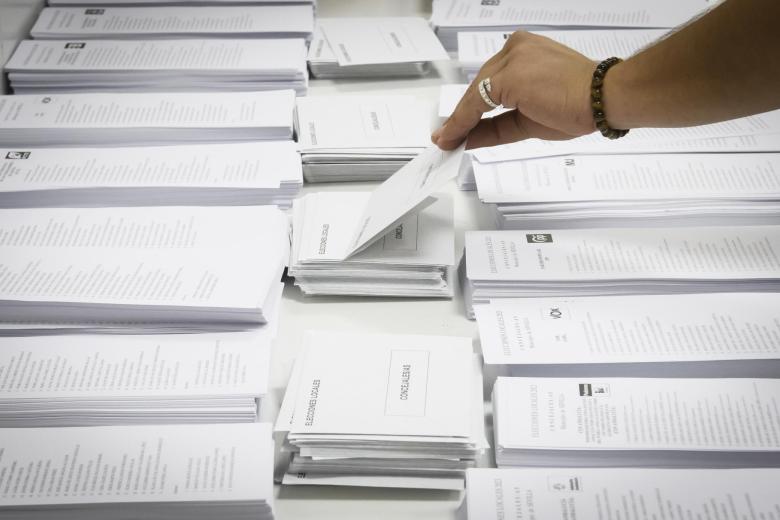 Una persona coge un sobre para meter su papeleta y votar en un colegio electoral de Sevilla.