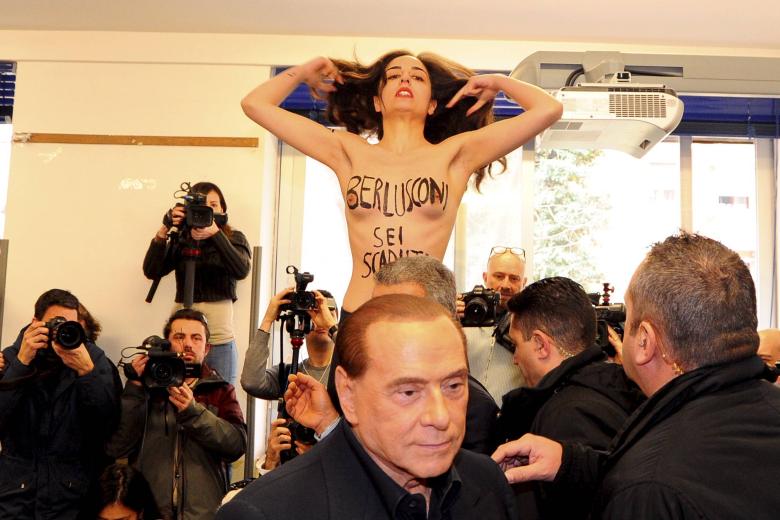 Una feminista protesta contra Berlusconi mientras emitía su voto en las elecciones regionales de 2018
