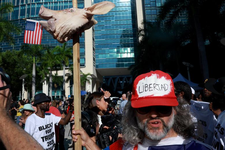 Osmany Estrada sostiene un poste con una cabeza de cerdo clavada afuera de la Corte Federal donde comparecerá Trump