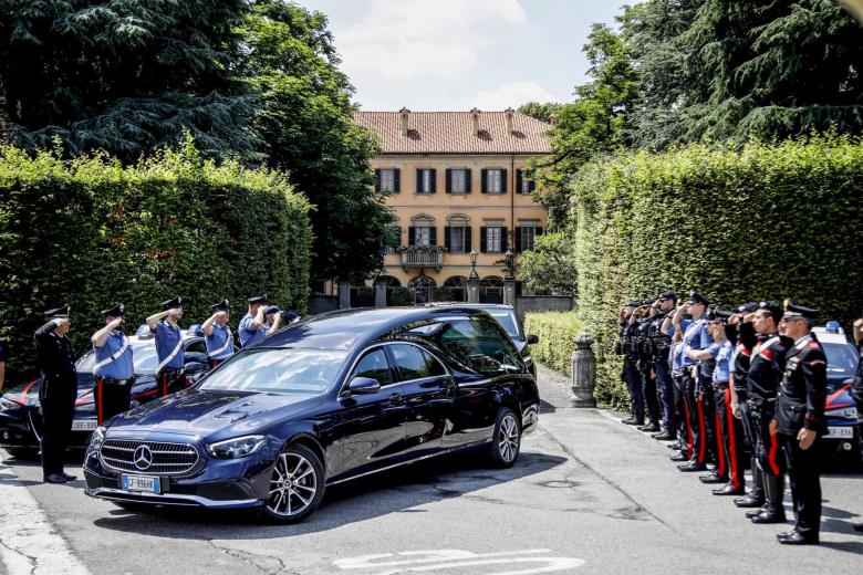 Los Carabinieri italianos saludan mientras el coche fúnebre que transporta el féretro de Silvio Berlusconi abandona Villa San Martino, la residencia del ex primer ministro italiano Silvio Berlusconi, en Arcore, cerca de Milán, norte de Italia.