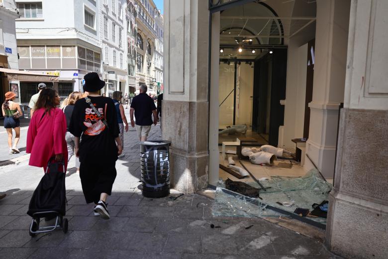 Los peatones pasan frente a una tienda dañada y saqueada en el centro de Marsella