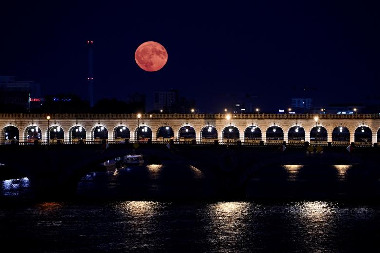 Esta fotografía tomada en París el 3 de julio de 2023 muestra la superluna de julio, conocida como Luna del Ciervo, con el 'Pont de Bercy' en primer plano. (Foto de Stefano RELLANDINI / AFP)