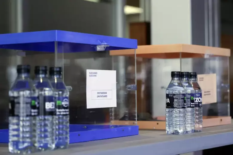 Urnas y botellas de agua dispuestas para los miembros de las mesas electorales durante el montaje del colegio electoral para las Elecciones Generales del 23-J