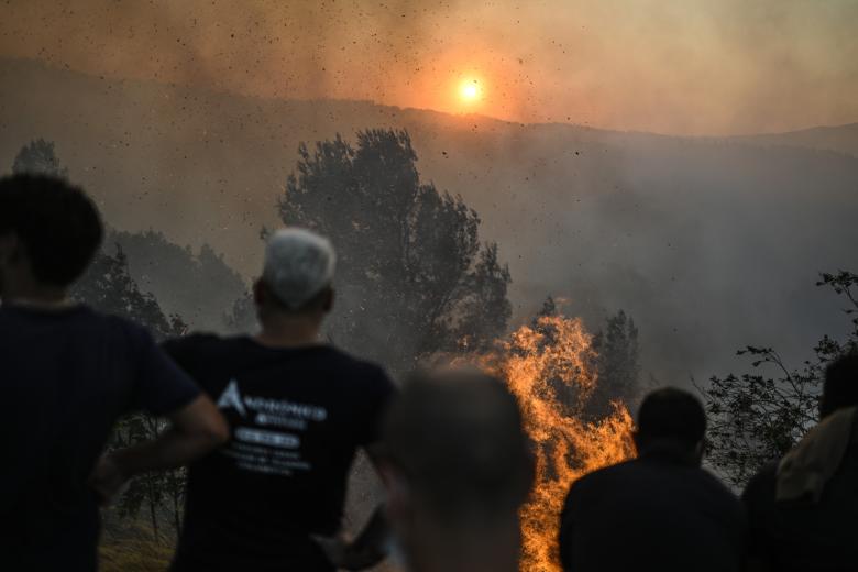 Ciudadanos observan la progresión de un incendio forestal a medida que se acerca al pueblo de Zambujeiro, en Cascais (Portugal)