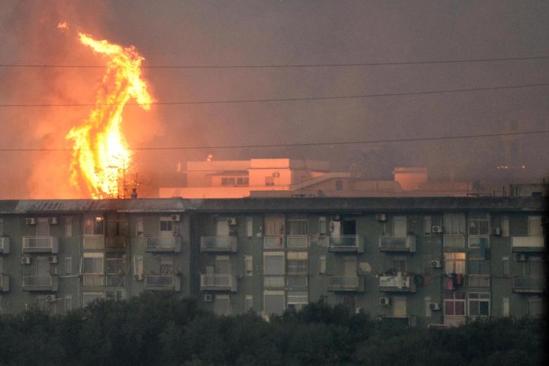 Una columna de fuego se eleva tras un bloque de viviendas en el área de Monte Grifone en la ciudad de Ciaculli, cerca de Palermo