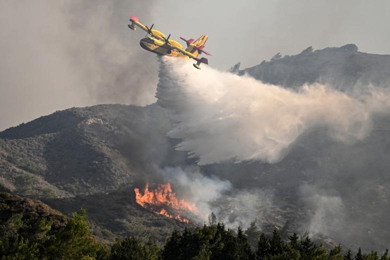 Un avión de extinción de incendios arroja agua sobre un fuego cerca del pueblo de Vati, en la parte sur de la isla griega de Rodas