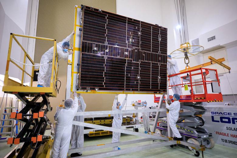 En esta imagen del 18 de julio de 2023, un equipo de la NASA ayuda a colocar paneles solares para la nave espacial Psyche de la agencia en un soporte dentro de las instalaciones de operaciones espaciales de Astrotech cerca del Centro Espacial Kennedy en Florida