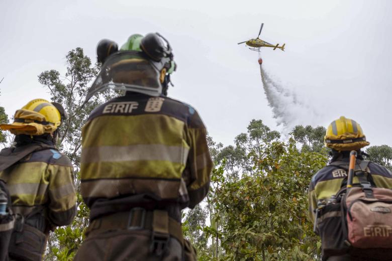 Los equipos de EIRIF de la isla de El Hierro, que colaboran en las labores de enfriamiento de las zonas afectadas por el incendio en Tenerife, observan como los medios aéreos realizan descargas de agua en la zona de La Hornaca en el municipio del Rosario.