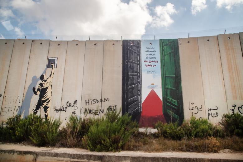 Una pintada con la bandera Palestina en el muro levantado por Israel en la blue line