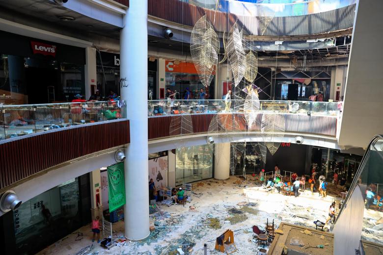 Personas recuperando objetos en un centro comercial de una zona afectada por el paso del huracán Otis