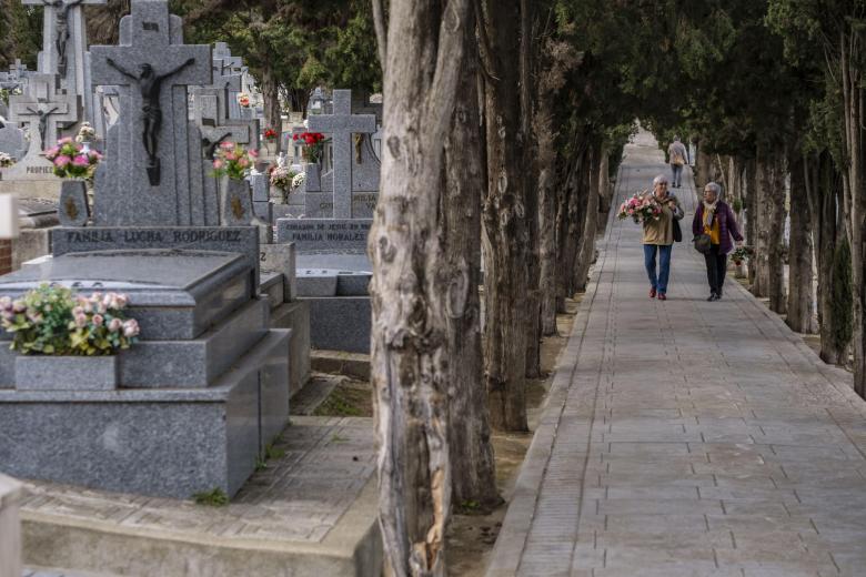 Dos mujeres conversan mientras se dirigen a dejar flores en la tumba de algún ser querido en el cementerio de Toledo