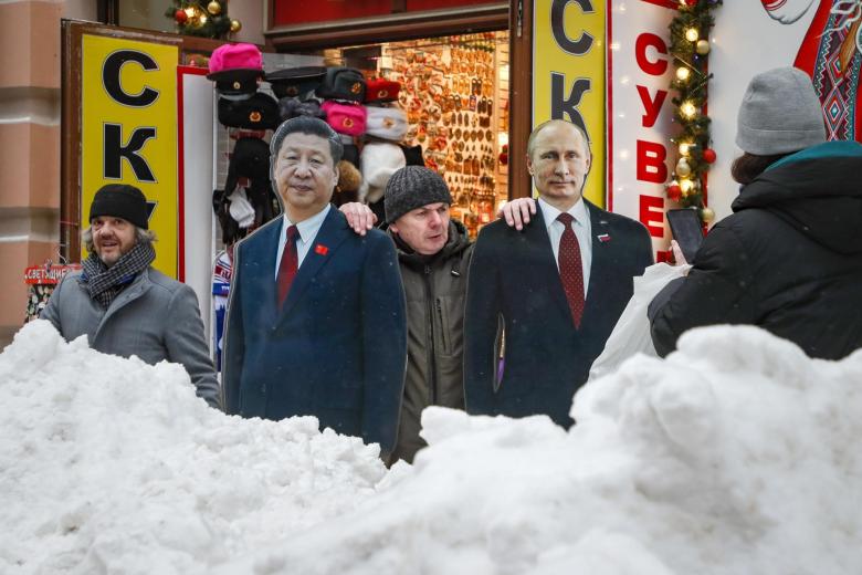 Un hombre posa junto a dos figuras de cartón del presidente chino Xi Jinping y del presidente ruso Vladimir Putin después de una gran nevada en Moscú