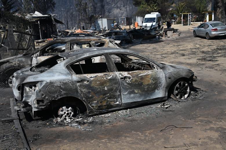 View of burnt vehicles after a fire that affected the hills in Quilpue comune, Viña del Mar, Chile on February 3, 2024. The region of Valparaiso and Viña del Mar, in central Chile, woke up on Saturday with a partial curfew to allow the movement of evacuees and the transfer of emergency equipment in the midst of a series of unprecedented fires, authorities reported. (Photo by RODRIGO ARANGUA / AFP)