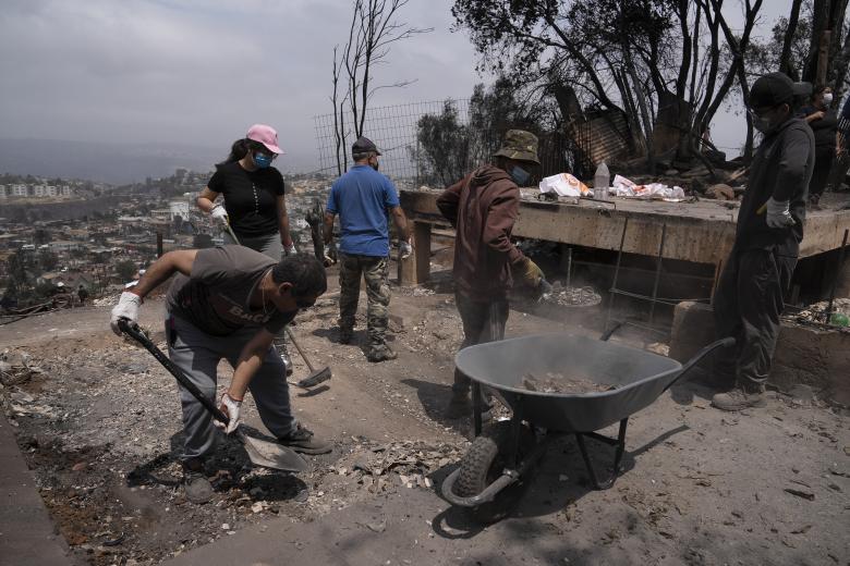Personas del campamento irregular “Pompeya” recogen escombros, tras los incendios del día viernes 2 de febrero