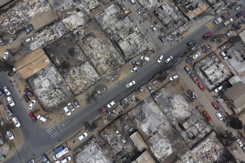 Personas del campamento irregular “Pompeya” recogen escombros, tras los incendios del día viernes 2 de febrero