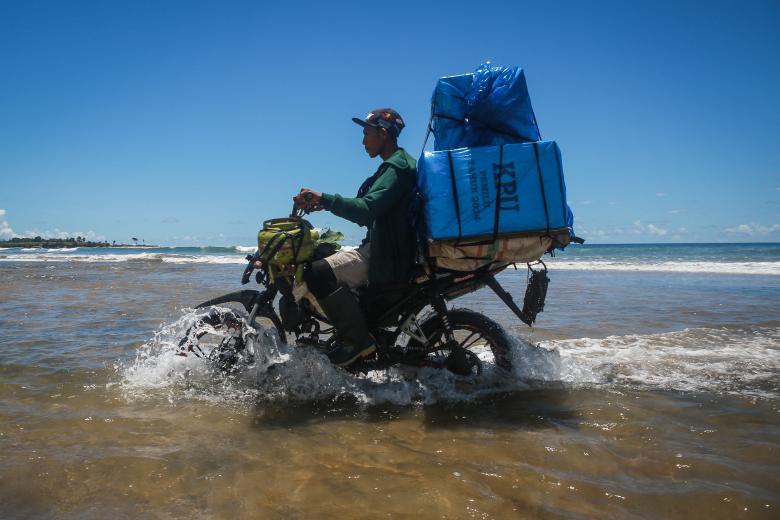 Un miembro de la unidad de logística de la Comisión Electoral General (KPU) conduce una motocicleta para entregar materiales electorales en Lampung, Indonesia