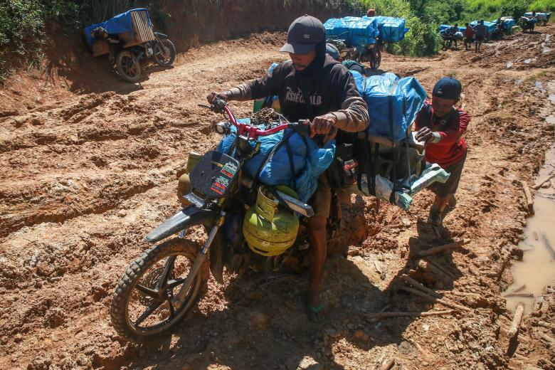 Una columna de motocicletas cargadas con material electoral de la Comisión Electoral General (KPU) avanzan en medio del fango en Lampung, Indonesia