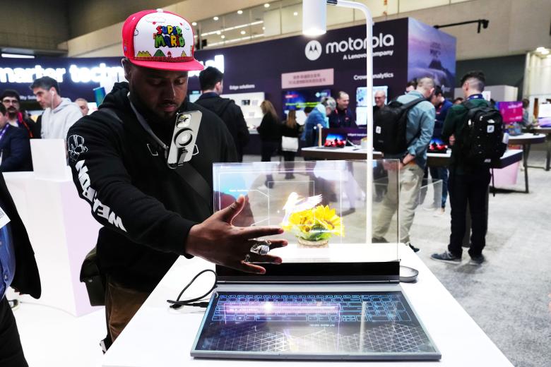 A visitor tests the transparent display of new Lenovo ThinkBook laptop on the first day of the Mobile World Congress (MWC), the telecom industry's biggest annual gathering, in Barcelona on February 26, 2024. The world's biggest mobile phone fair throws open its doors in Barcelona with the sector looking to artificial intelligence to try and reverse declining sales. (Photo by PAU BARRENA / AFP)