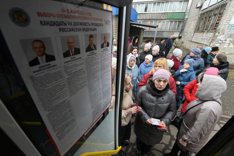 Los votantes hacen cola frente a un autobús transformado en colegio electoral durante las elecciones presidenciales de Rusia en Makiivka, región de Donetsk, Ucrania controlada por Rusia