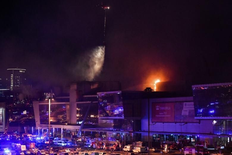 Un helicóptero de extinción de incendios arroja agua sobre la sala de conciertos Crocus City Hall en llamas tras el tiroteo en Krasnogorsk, en las afueras de Moscú