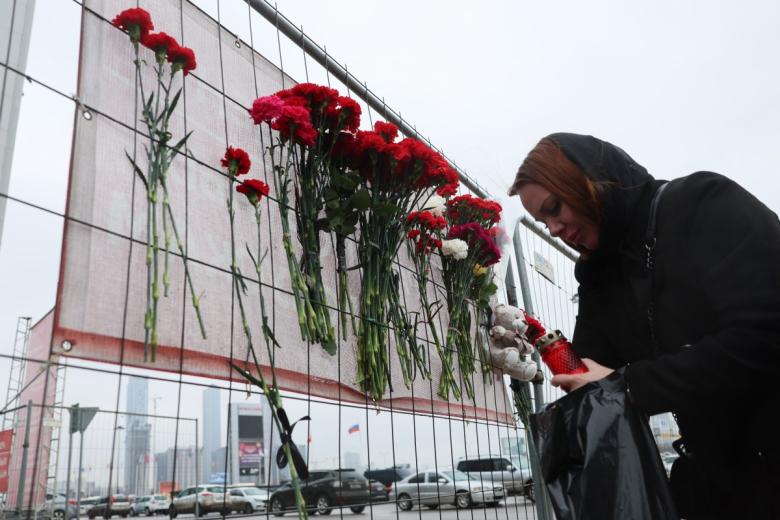 Una mujer muestra sus respetos con velas en un monumento improvisado frente al Ayuntamiento de Crocus, un día después del ataque.