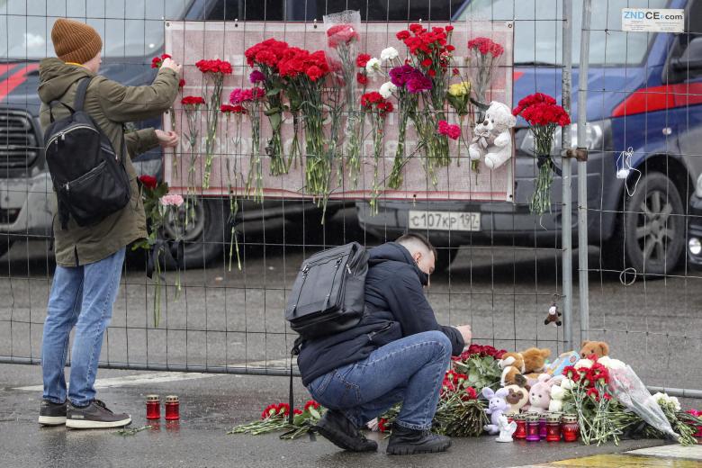 La gente trae flores a las puertas de la sala de conciertos quemada del Crocus City Hall tras el ataque terrorista en Krasnogorsk, en las afueras de Moscú, Rusia, el 23 de marzo de 2024.