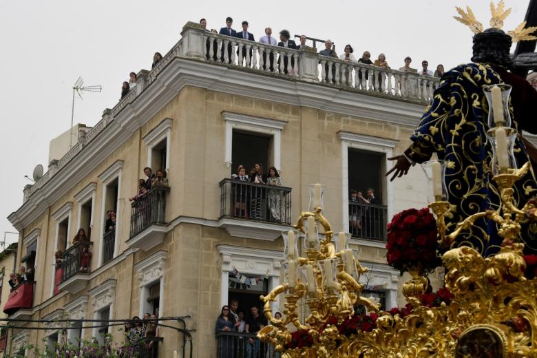 Los vecinos de Sevilla observan desde los balcones cómo los penitentes de la hermandad de La Paz participan en la procesión del Domingo de Ramos.